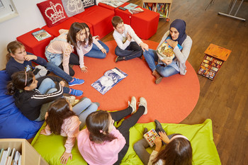 Im Leseclub Monheim liest eine Engagierte Kindern aus einem Buch vor